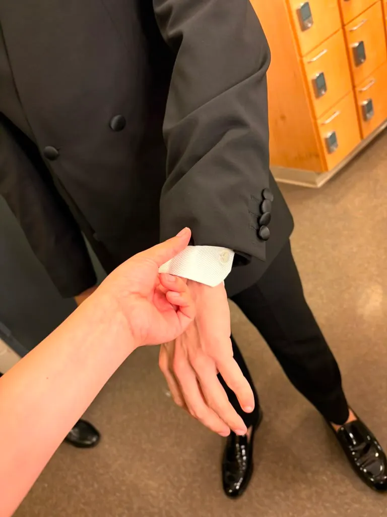 Checking sleeve length against the shirt cuff at the fitting