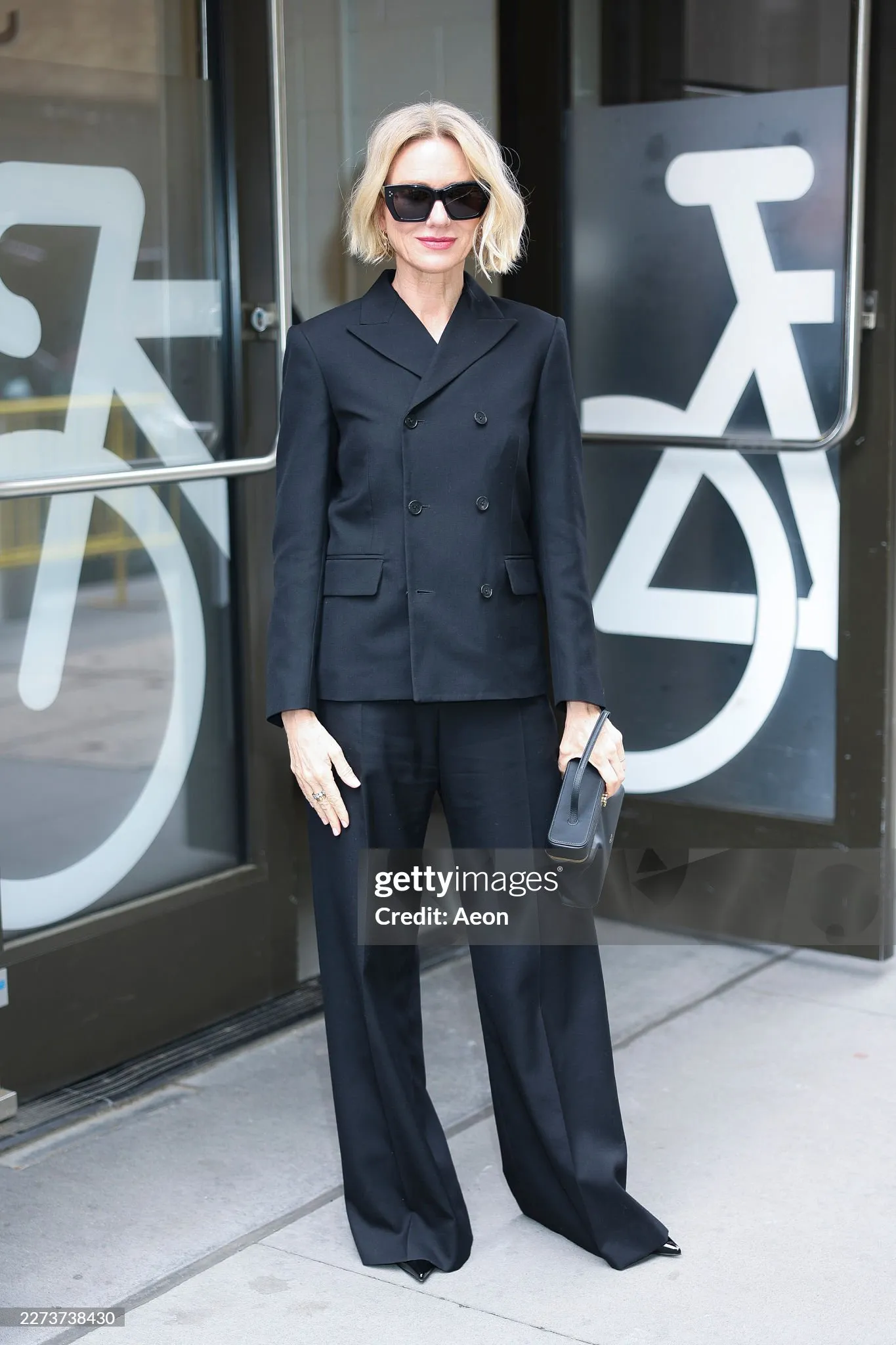 Naomi Watts in a black double-breasted blazer and wide trousers